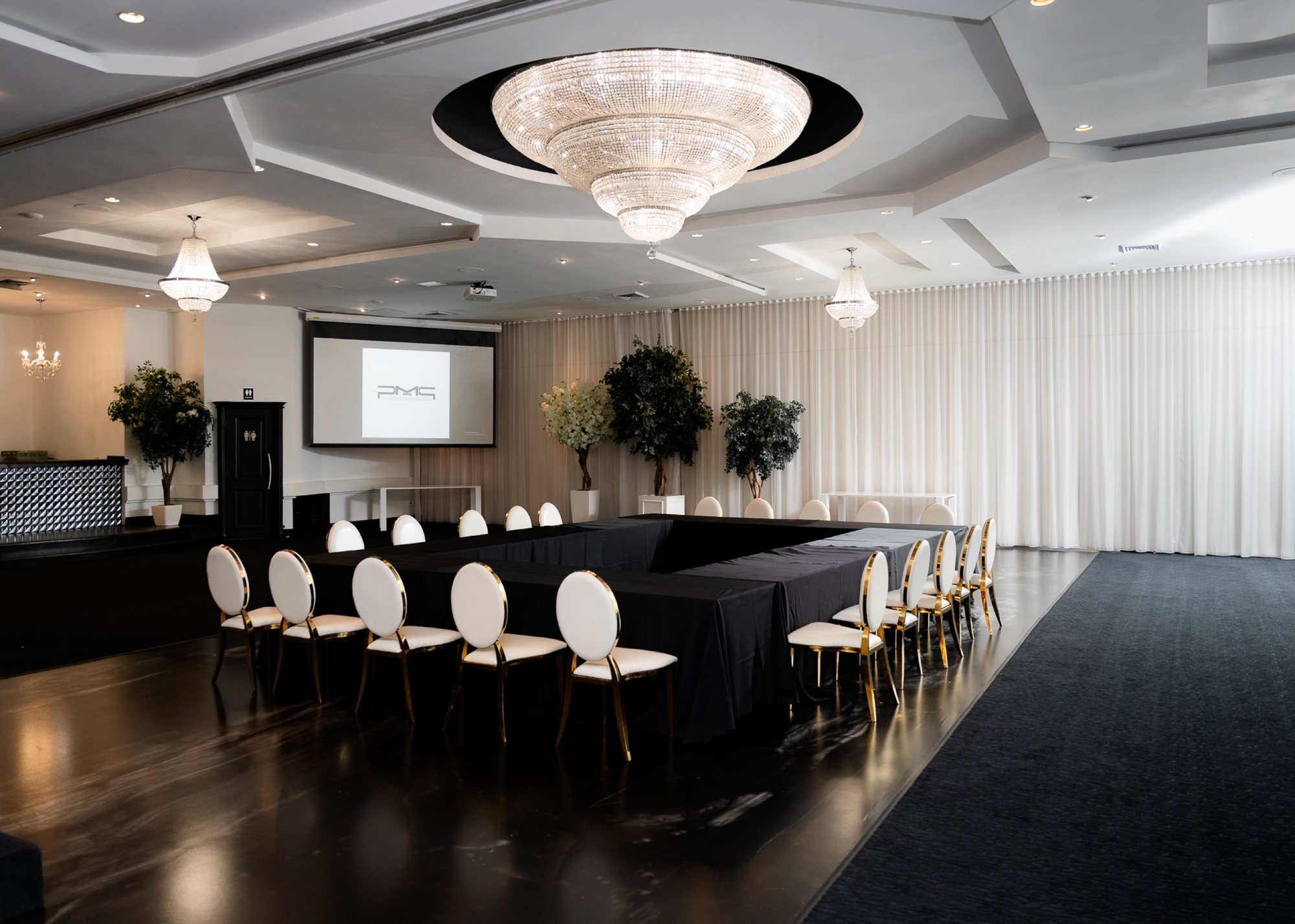 Tables en U avec chaises blanches sous un lustre